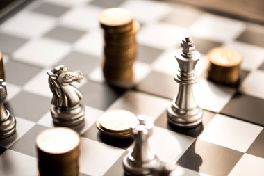 satranç taşları ve sikkeler üzerinde bir satranç tahtası yığını