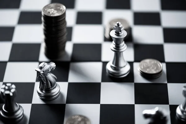 Chess pieces and stack of coins on a chessboard — Stock Photo, Image