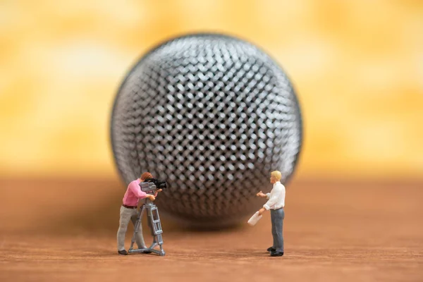 miniature people speak to microphone