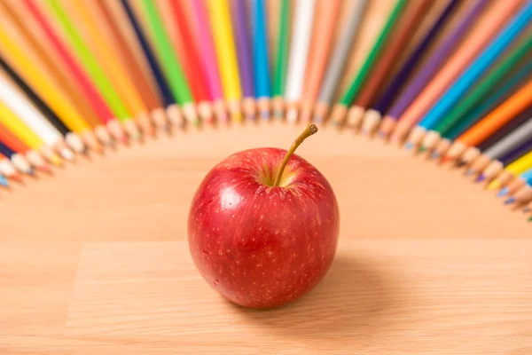 red apple with pencils around