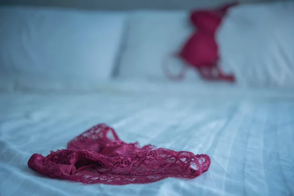Kırmızı kadınlar beyaz yatakta iç çamaşırı giyiyor. — Stok fotoğraf