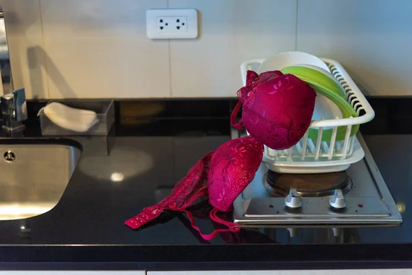 Rode vrouw beha op fornuis in de keuken — Stockfoto