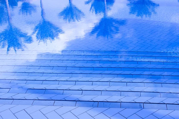 Reflejos de palmeras en el agua azul de una piscina — Foto de Stock