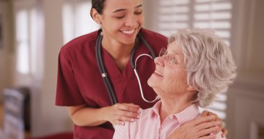 Hispanic female nurse looking and smiling with senior caucasian woman clipart