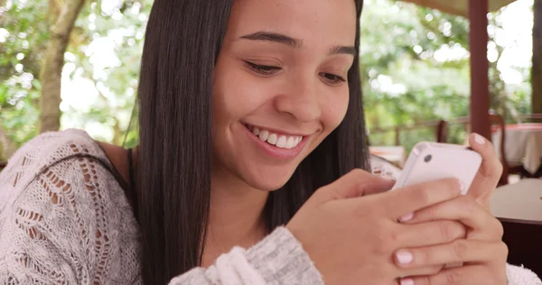 Menina hispânica jovem lendo texto do telefone celular no restaurante — Fotografia de Stock