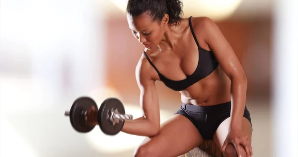 Mixed-race millennial womanlifting weights at the gym