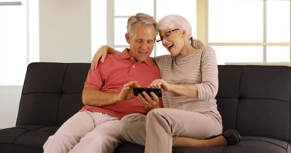 Adultos Mayores Modernos Sentados Sofá Viendo Videos Teléfono Inteligente —  Fotos de Stock