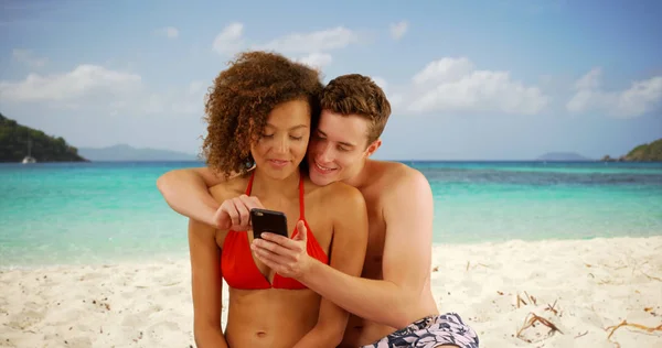 ビーチでスマート フォンを使用して美しい若いカップル — ストック写真