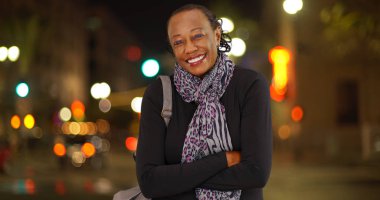 Meşgul bir sokak köşesinde soğuk havalarda gülüyor eski bir Afrikalı-Amerikalı kadın portresi