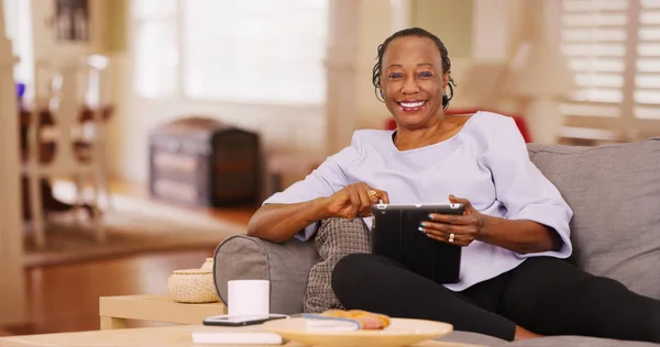 Una Anciana Negra Felizmente Usa Tableta Mientras Mira Cámara —  Fotos de Stock