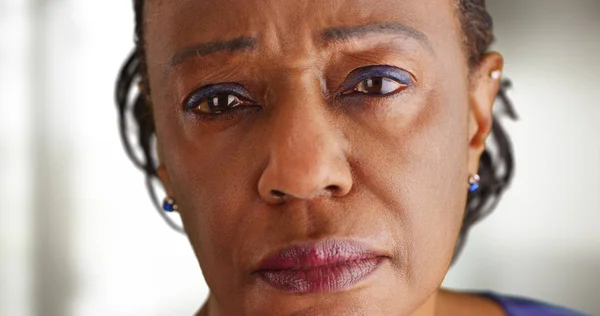 A close-up of a elderly black woman looking sad