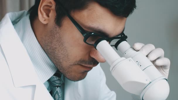 Joven científico mirando a través del microscopio — Vídeos de Stock