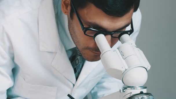 Joven científico mirando a través del microscopio — Vídeos de Stock