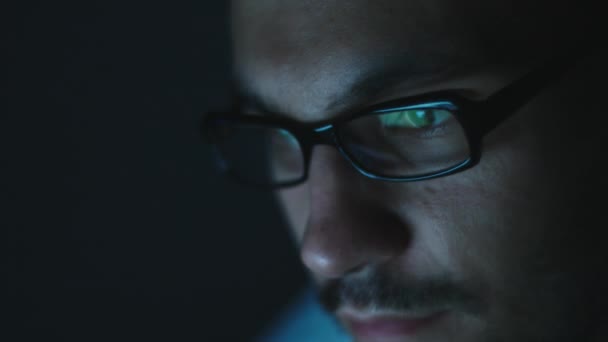 Young man with glass work on laptop in the dark — Stock Video