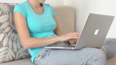 Kanepeye siting ve dizüstü bilgisayarda çalışan kadın