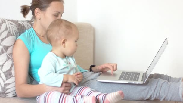 Mamá y su hijo pequeño ven algo en la pantalla del portátil — Vídeo de stock