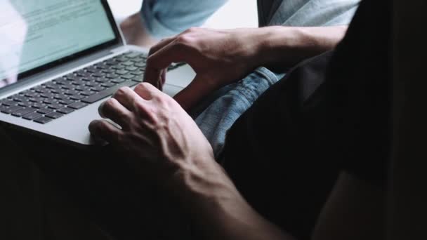Le gars est assis sur le rebord de la fenêtre et court sur l'ordinateur portable sur ses genoux . — Video