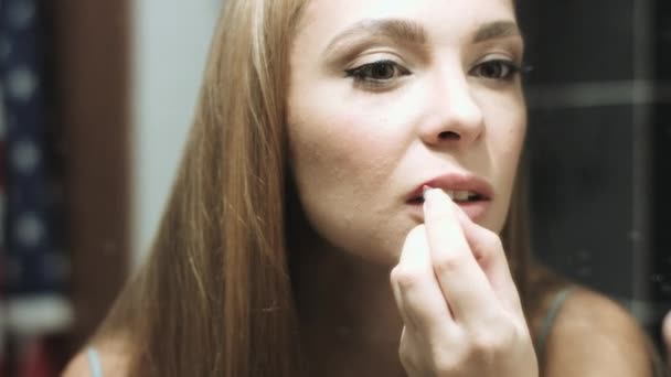 Beautiful blond woman paints her lips — Stock Video