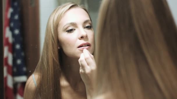 Beautiful blond woman paints her lips — Stock Video