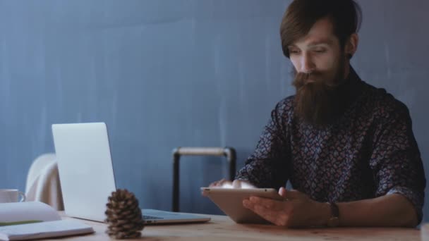 Joven macho usando tableta en el escritorio — Vídeos de Stock