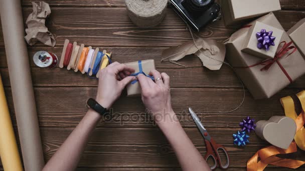 Person dekoriert verpacktes Geschenk mit blauer Schleife — Stockvideo