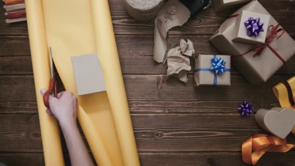 Person schneidet Papier und verpackt Geschenk — Stockvideo