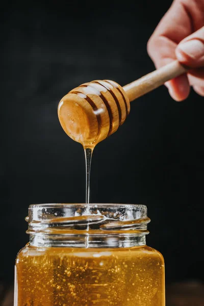 Person dipping honey stick in — Stock Photo, Image