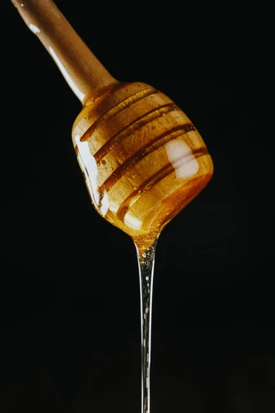 Person dipping honey stick in — Stock Photo, Image