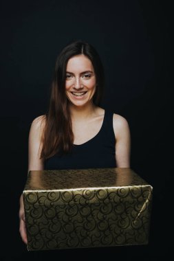 Genç kadın gülümseyerek ve hediye kutusu holding