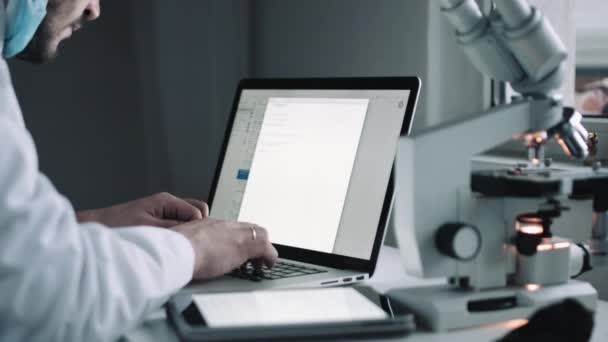 Vista lateral del científico que trabaja en el ordenador portátil — Vídeo de stock