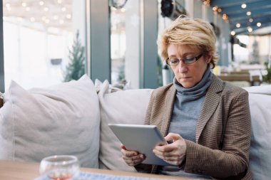 Orta yaş kadın Kafe oturan tablet ile