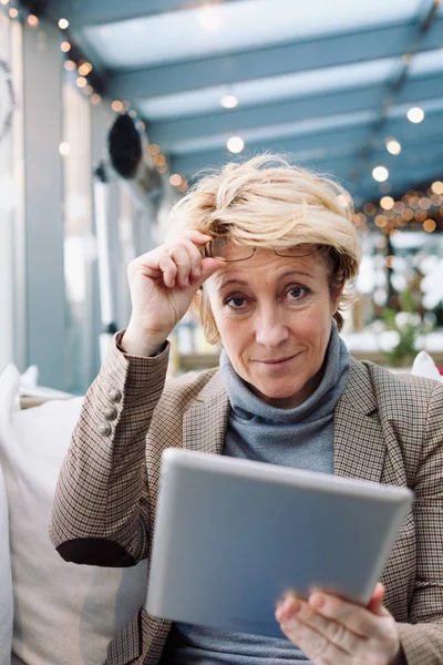 Mid age woman with tablet sitting cafe