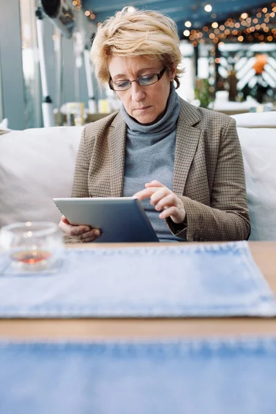 Mujer de mediana edad con la tableta café sentado — Foto de Stock