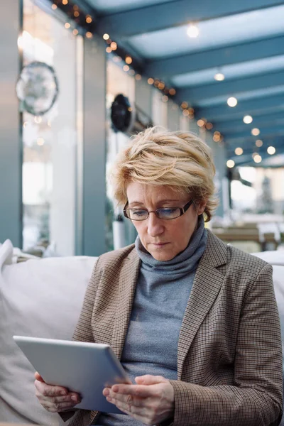 Mujer de mediana edad con la tableta café sentado — Foto de Stock