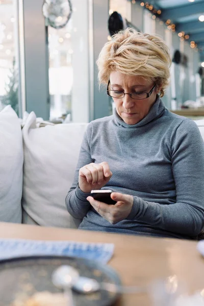 Mujer de mediana edad con teléfono celular café sentado — Foto de Stock