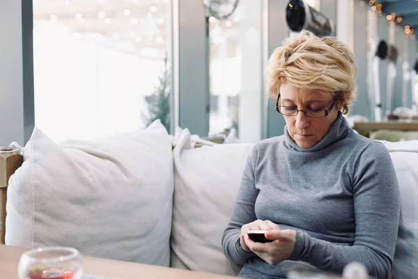 Mid age woman with cell phone sitting cafe