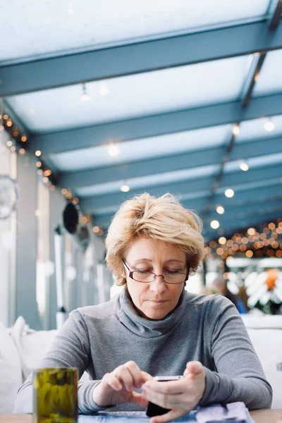 Mujer de mediana edad con teléfono celular café sentado — Foto de Stock