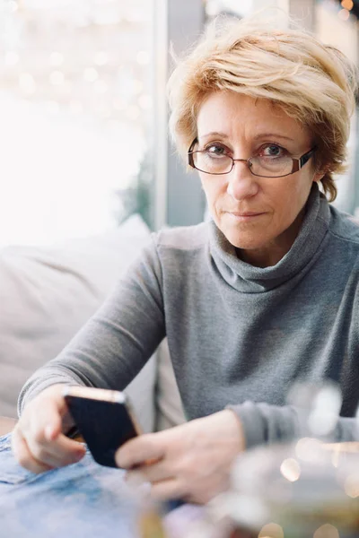 Mid age woman with cell phone sitting cafe — Stock Photo, Image