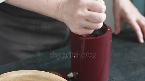 Mujer en el delantal vierte granos de café en la amoladora — Vídeo de stock