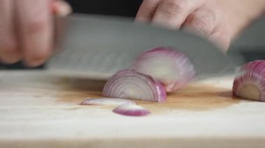 Yong adam aşçı önden görünümü bıçakla kesme tahtası üzerinde kırmızı soğan ince dilimler kesip.