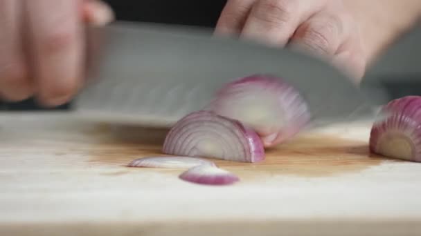 Yong adam aşçı önden görünümü bıçakla kesme tahtası üzerinde kırmızı soğan ince dilimler kesip. — Stok video