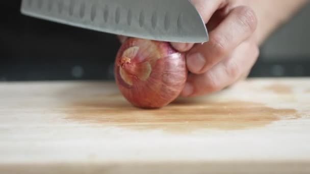 Vooraanzicht van yong man kok Snij dunne plakjes rode ui met mes op cutting Board. — Stockvideo