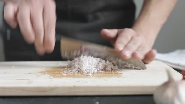 Front view of yong man cook cut thin slices of red onion with knife on cutting Board. — Stock Video