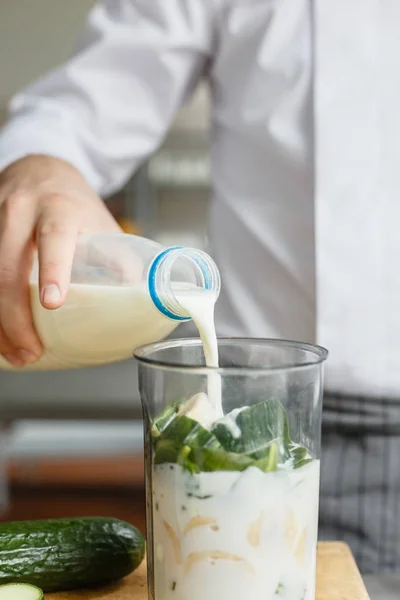 Mann schüttet Milch während Smoothie zubereitet — Stockfoto