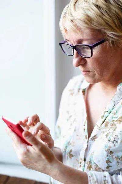 Mujer madura en gafas usando smartphone — Foto de Stock