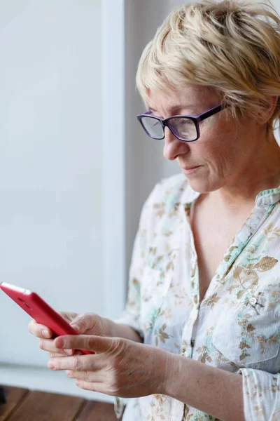 Mujer madura en gafas usando smartphone — Foto de Stock