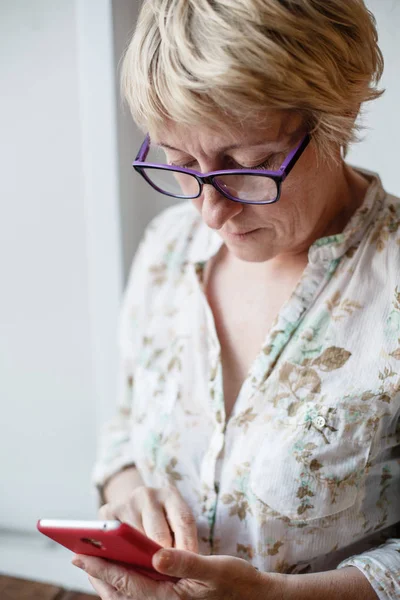 Mujer madura en gafas usando smartphone — Foto de Stock