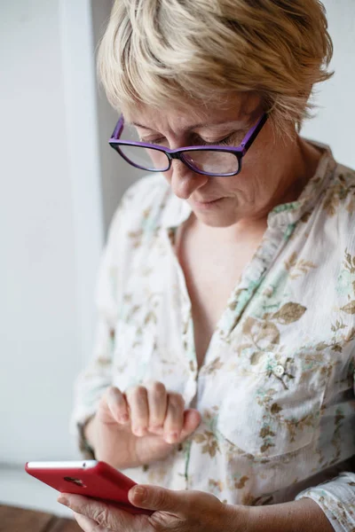 Mujer madura en gafas usando smartphone — Foto de Stock