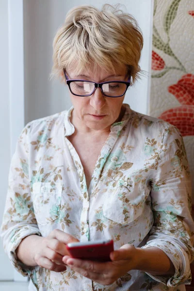 Mujer madura en gafas usando dispositivo — Foto de Stock