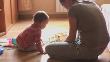 Anne ve çocuk yere oturma odasında oynarken.
